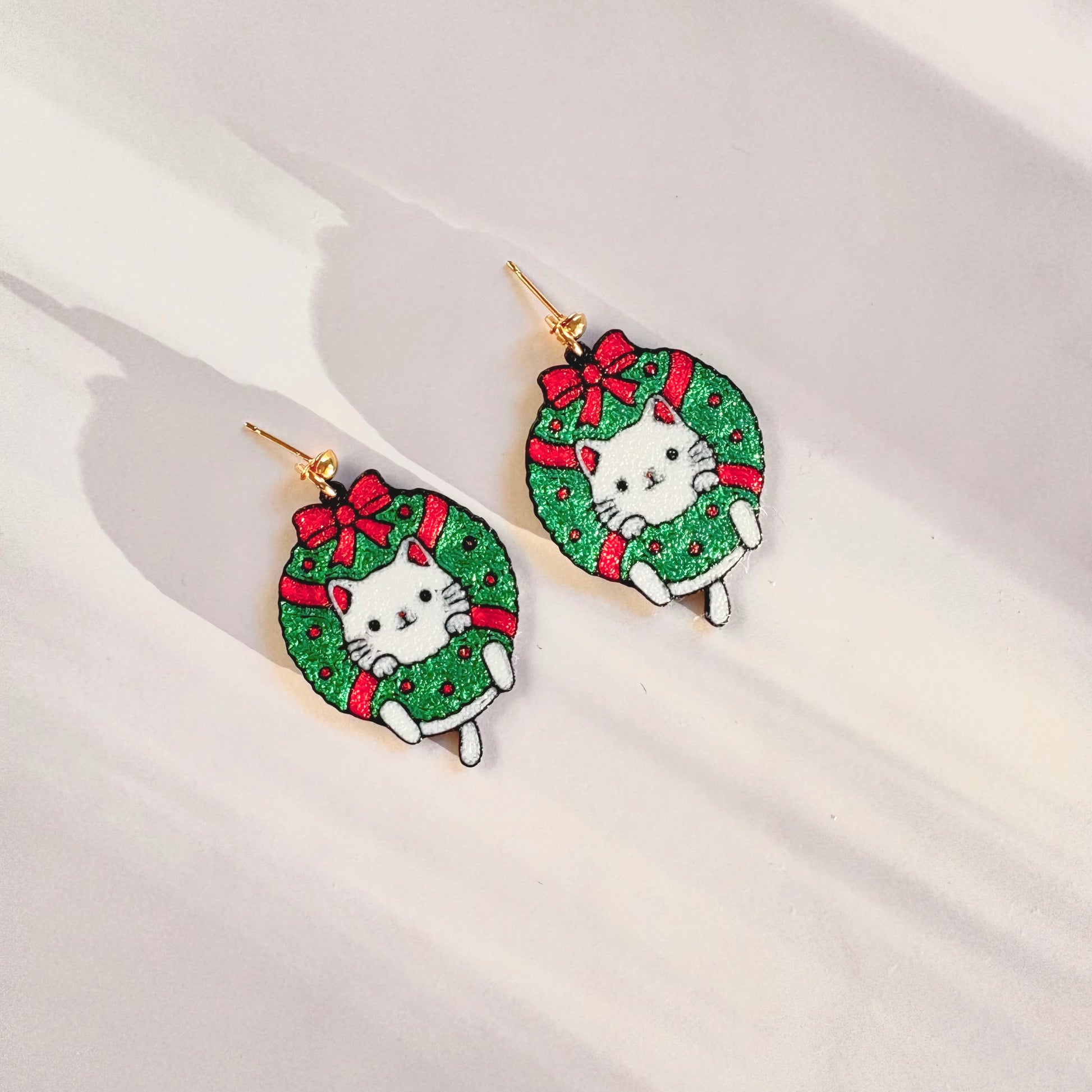 Christmas-themed earrings with cat designs on a white background