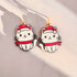Cat-shaped earrings with red hats and scarves on a light background