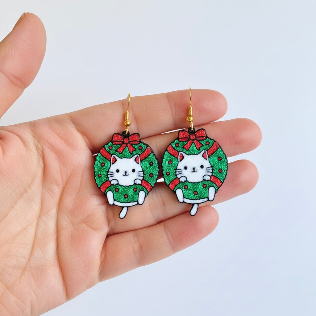 Hand holding Christmas-themed cat earrings with a white background