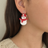 Snowman-shaped earring worn by a person with a neutral background