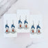 Hanging earrings featuring ghosts holding pumpkins and wearing beanie hats