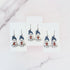 Hanging earrings featuring ghosts holding pumpkins and wearing beanie hats